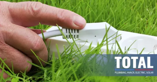 Hand touching a power strip on the grass